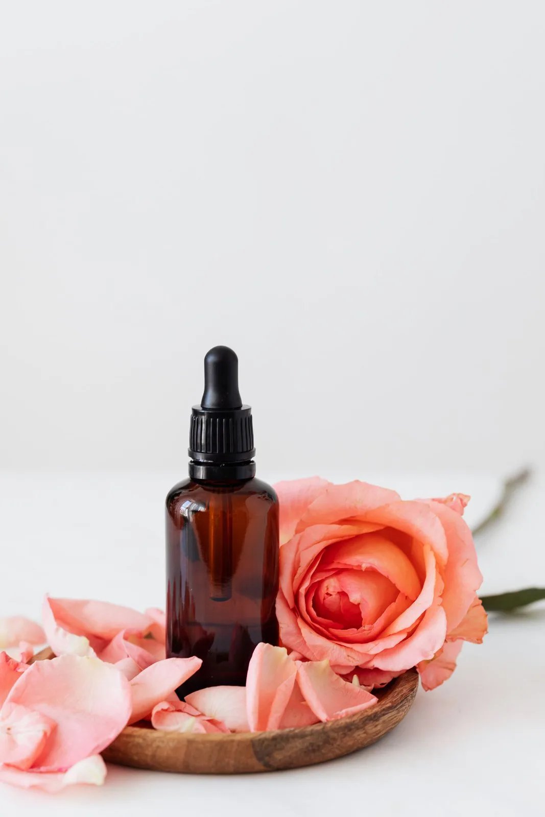 Amber dropper bottle of rose essence with rose petals